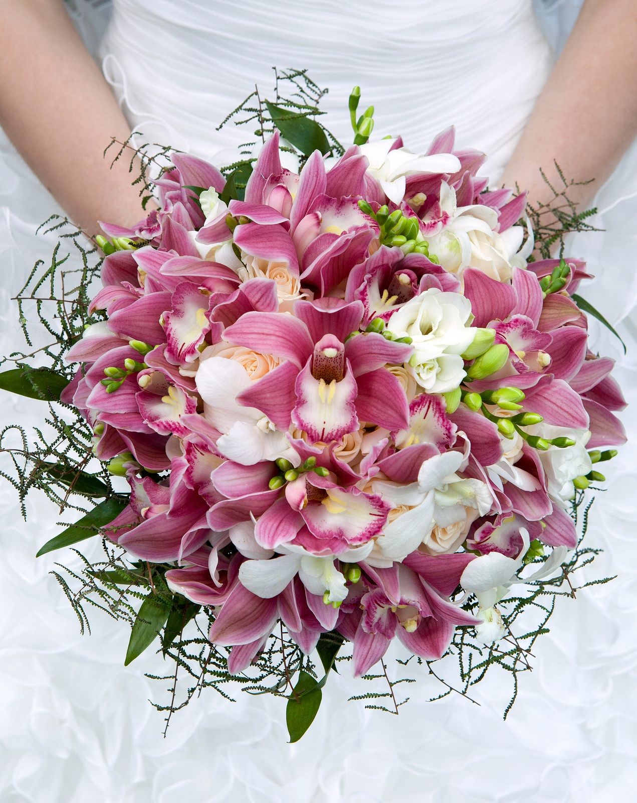 Happy bride carries a beautiful wedding bouquet of orchids and peonies